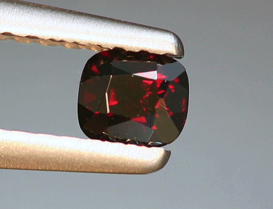 Пейнит темно-красный огранки «кушон», Мьянма, и кристалл бордового пейнита, окруженный десятками рубинов